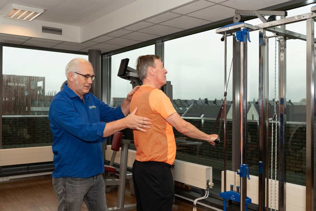 Fysiotherapeut helpt man met scoliose aan zijn rug in de oefenzaal
