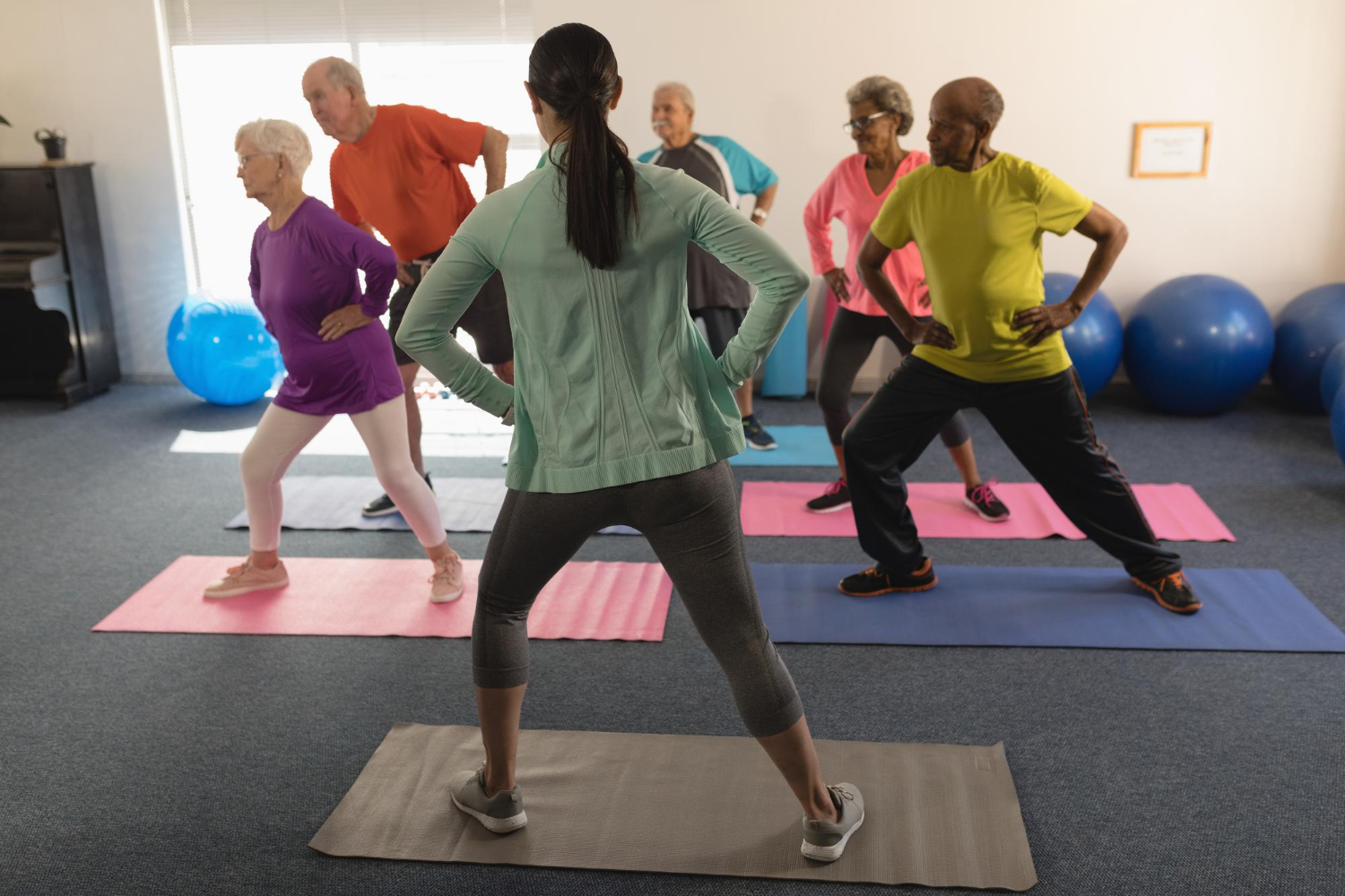 stress en rugklachten Groepje mensen probeert stress en rugklachten te voorkomen in de oefenzaal door oefeningen uit te voeren zoals pilates.